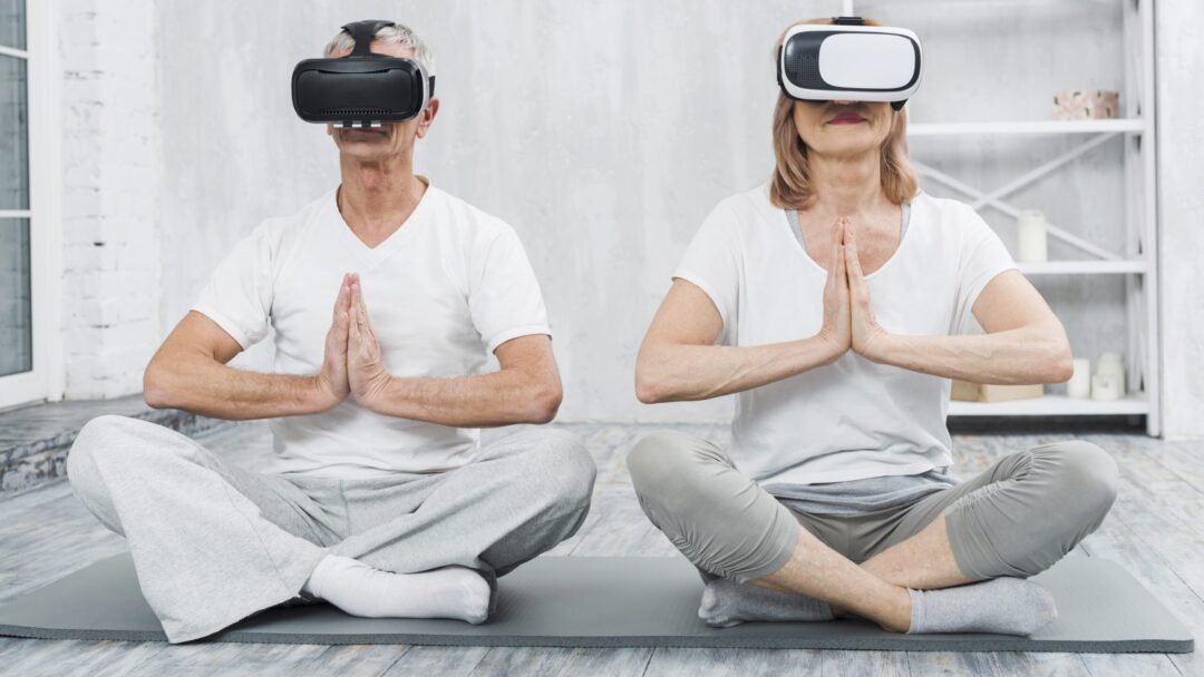 elder-couple-wearing-virtual-reality-headset-sitting-mat-with-praying-hands-gesture